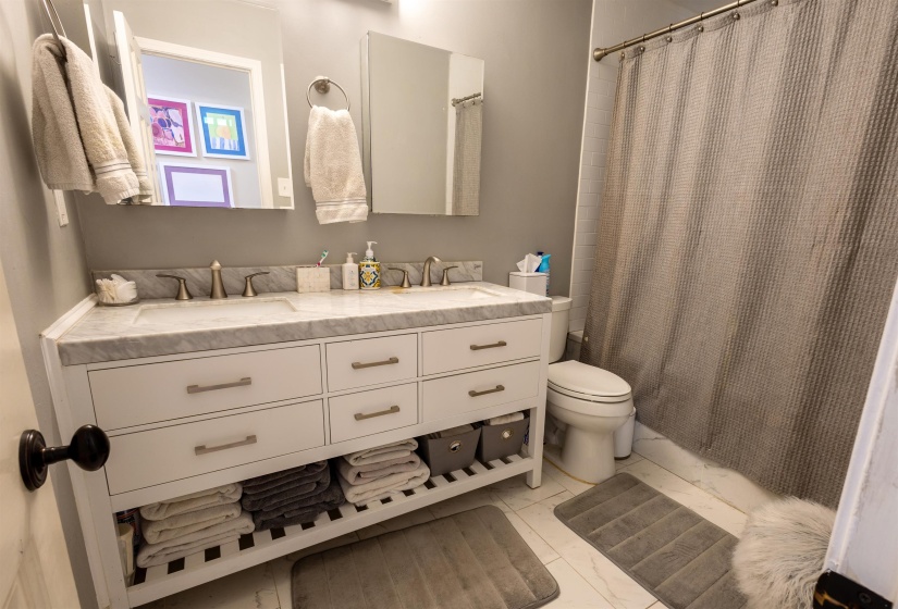Bathroom with double vanity and shower / bathtub combination with curtain
