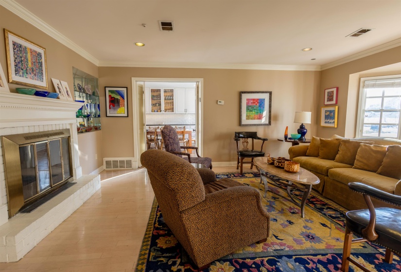 Living area with wood-type flooring, a fireplace, crown molding, and recessed lighting