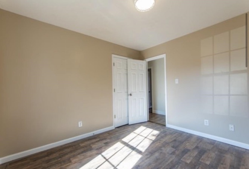 Unfurnished bedroom with dark wood-style flooring and a closet