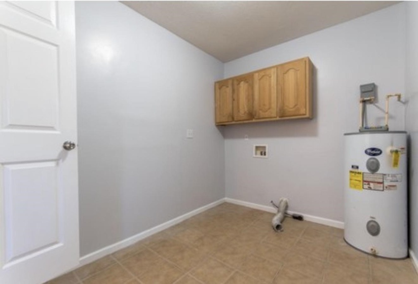 Washroom with water heater, cabinet space, and hookup for a washing machine
