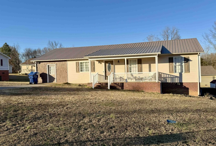 Single story home featuring covered porch, a metal roof, and a front lawn