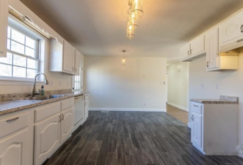 Kitchen featuring dark wood finished floors, white cabinets, decorative light fixtures, dishwasher, and ventilation hood