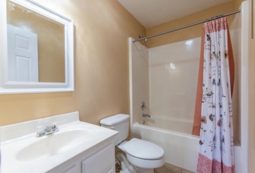 Bathroom with shower / bath combo with shower curtain, vanity, and tile patterned floors