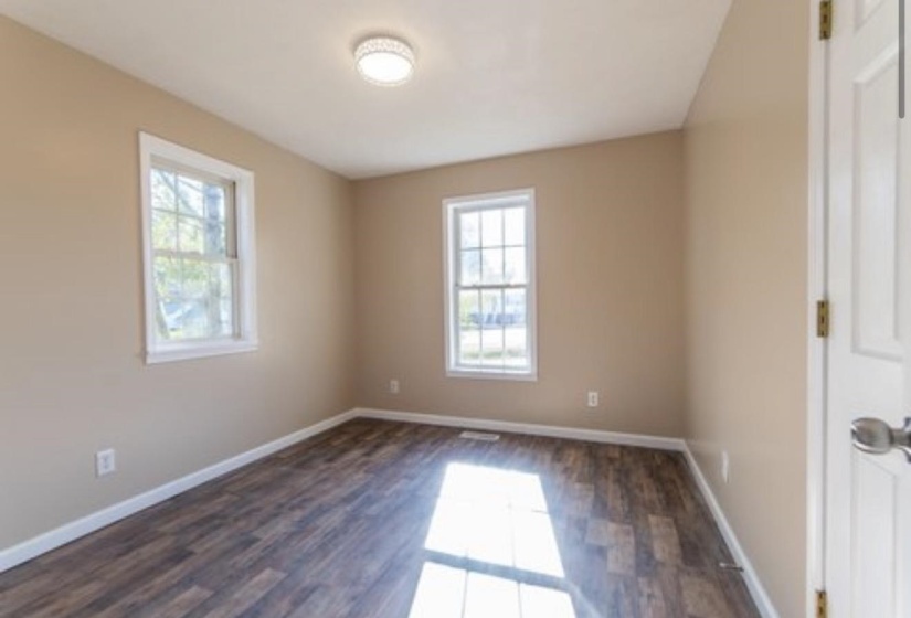Unfurnished room with dark wood-style flooring and plenty of natural light