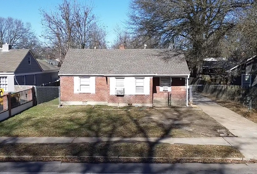 View of front facade featuring a shingled roof, brick siding, and a chimney