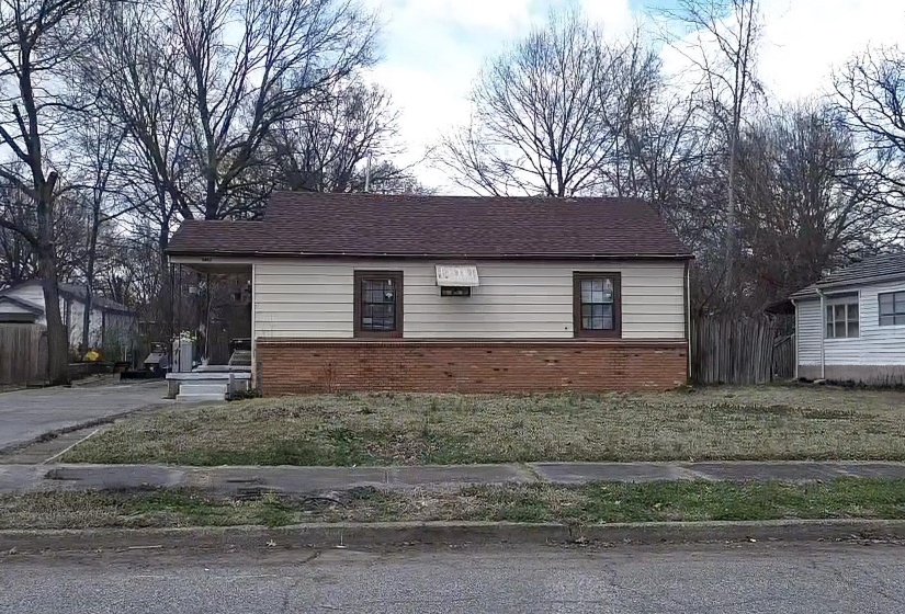 View of home's exterior with brick siding and a lawn