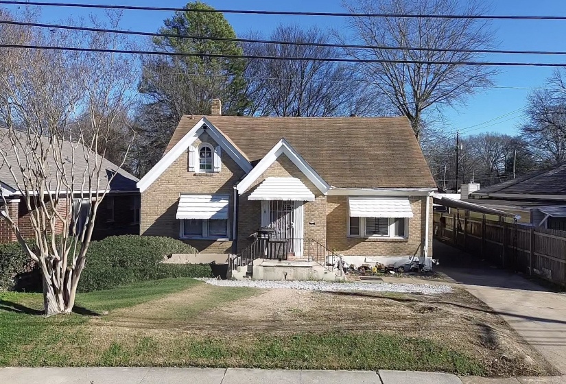 View of front facade with brick siding, a chimney, a front lawn, and a shingled roof