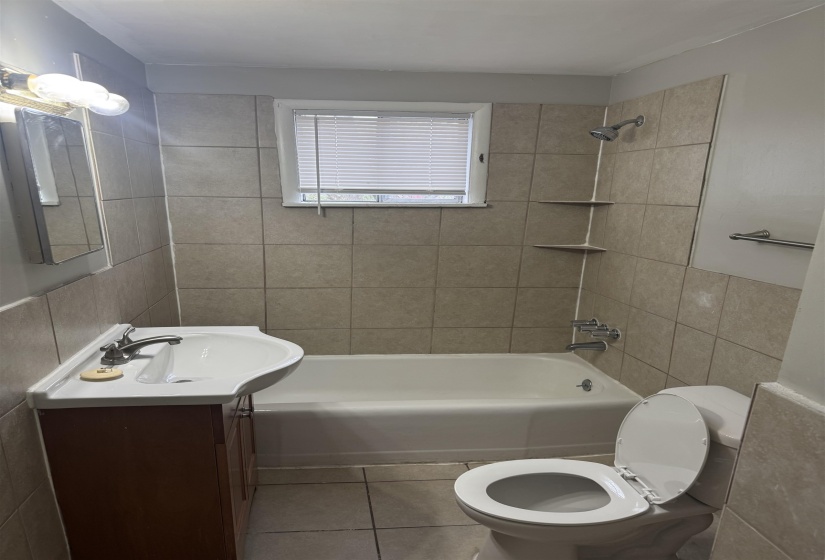 Bathroom with vanity, tile walls, shower / washtub combination, and tile patterned flooring