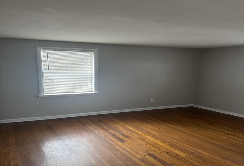 Empty room featuring dark wood-style floors and baseboards