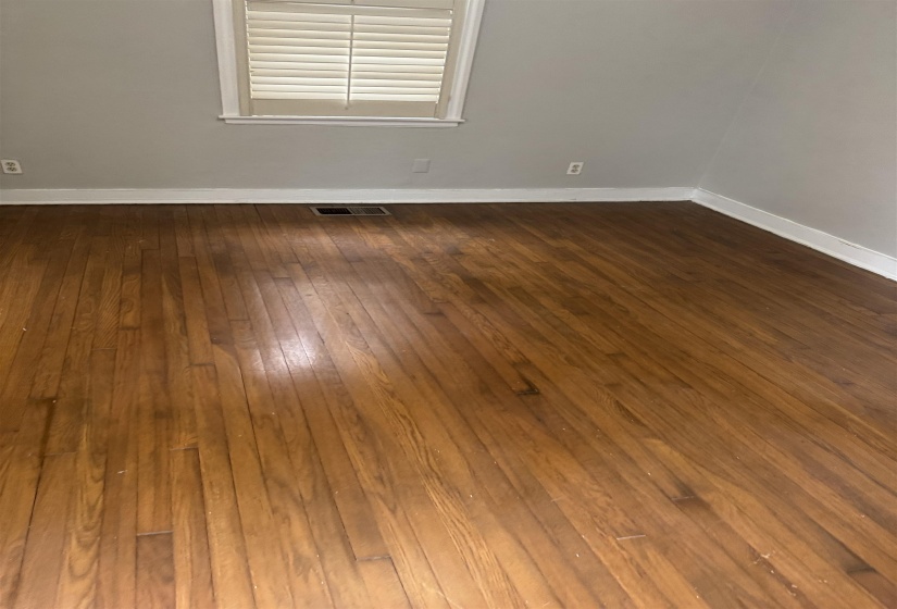 Empty room featuring dark wood finished floors and baseboards