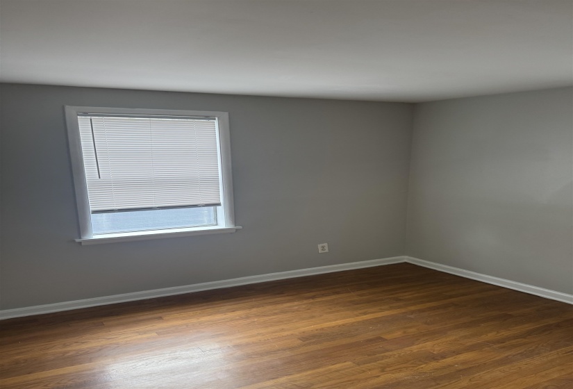 Spare room featuring dark wood-type flooring and baseboards