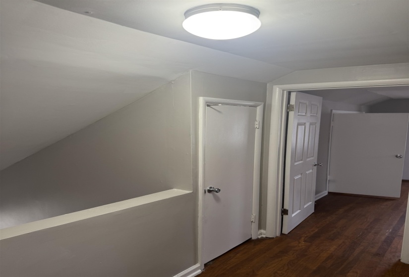 Hallway featuring vaulted ceiling and dark wood finished floors