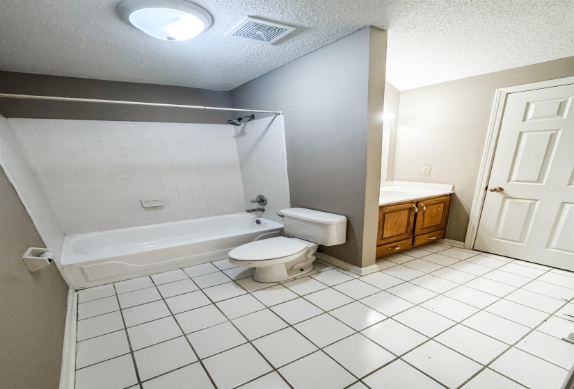 Full bath with vanity, shower / bath combination, a textured ceiling, and light tile patterned floors