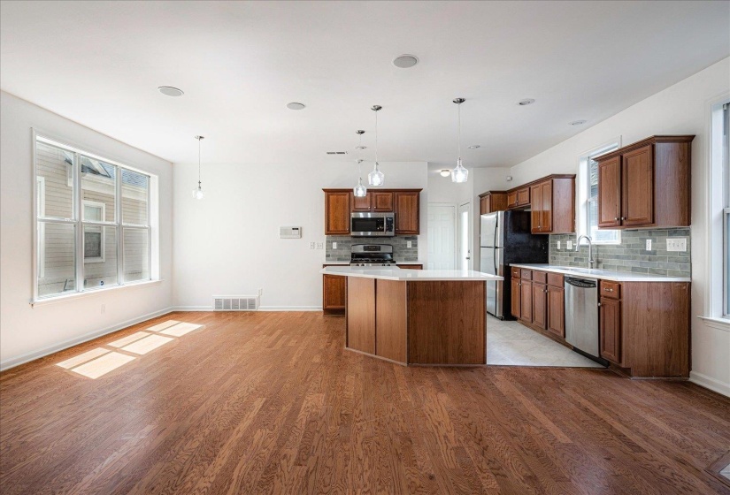 Kitchen with backsplash, decorative light fixtures, light countertops, and brown cabinetry