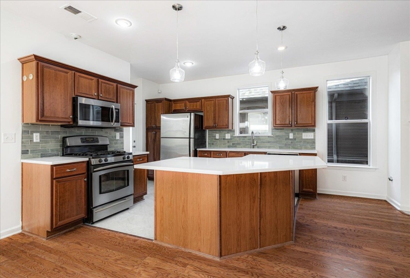 Kitchen featuring stainless steel appliances, pendant lighting, decorative backsplash, and a center island