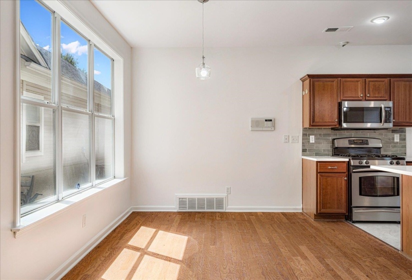 Kitchen with appliances with stainless steel finishes, tasteful backsplash, brown cabinets, pendant lighting, and light wood-style floors