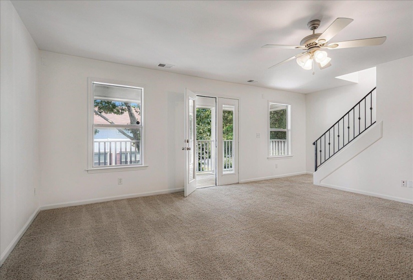 Unfurnished living room with carpet floors, stairs, and ceiling fan