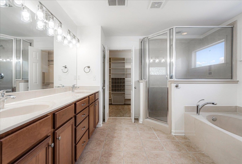 Bathroom with light tile patterned flooring, a stall shower, a bath, double vanity, and a spacious closet
