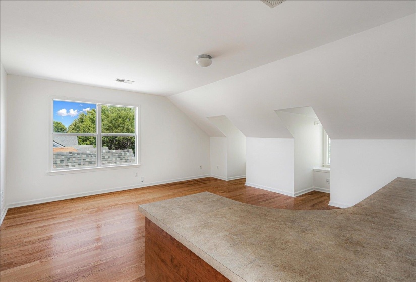 Additional living space with light wood-type flooring and lofted ceiling