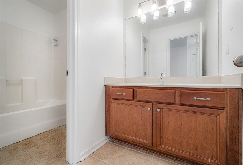 Bathroom featuring bathing tub / shower combination, vanity, and light tile patterned flooring