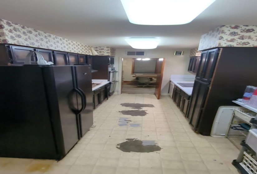 Kitchen featuring freestanding refrigerator, light flooring, light countertops, and wallpapered walls