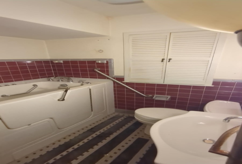 Full bath featuring a garden tub, tile walls, and wainscoting