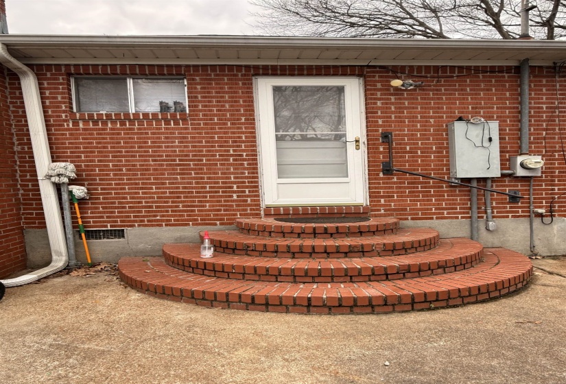 Property entrance with brick siding and crawl space