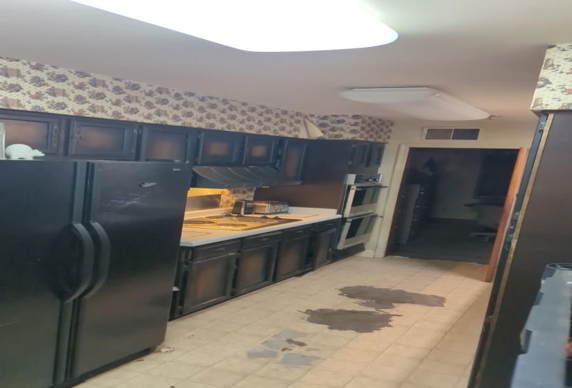 Kitchen featuring freestanding refrigerator, light countertops, light flooring, electric cooktop, and under cabinet range hood