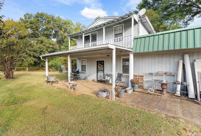 View of front facade with a balcony, a front yard, a metal roof, and a patio