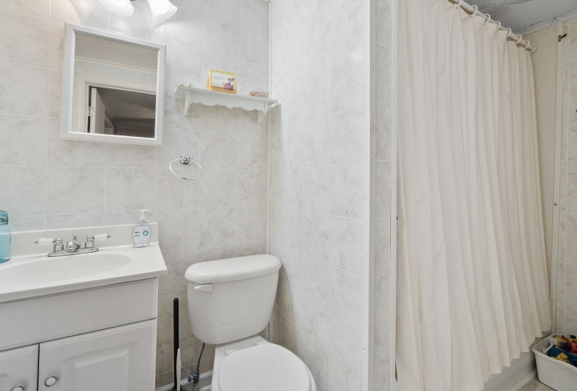 Full bath with a shower with curtain, tile walls, and vanity