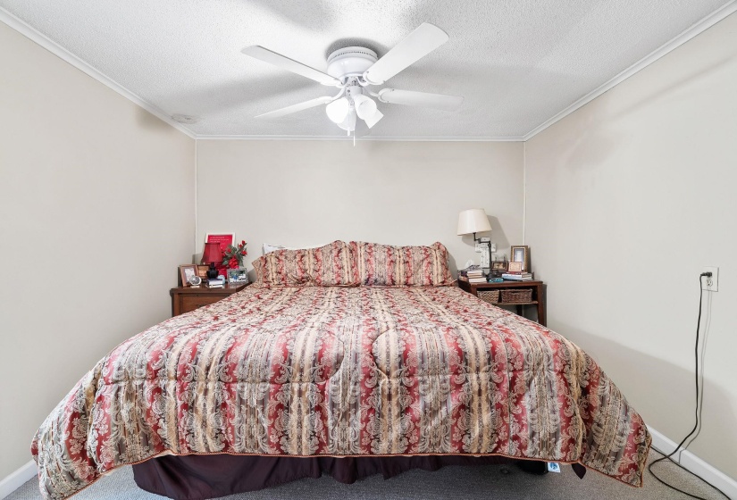 Carpeted bedroom with a textured ceiling, a ceiling fan, and ornamental molding