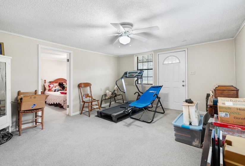 Exercise room with light carpet, a textured ceiling, ceiling fan, and crown molding