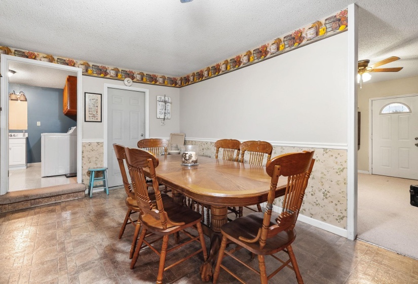 Dining area with a textured ceiling, wallpapered walls, washer / dryer, ceiling fan, and tile patterned floors