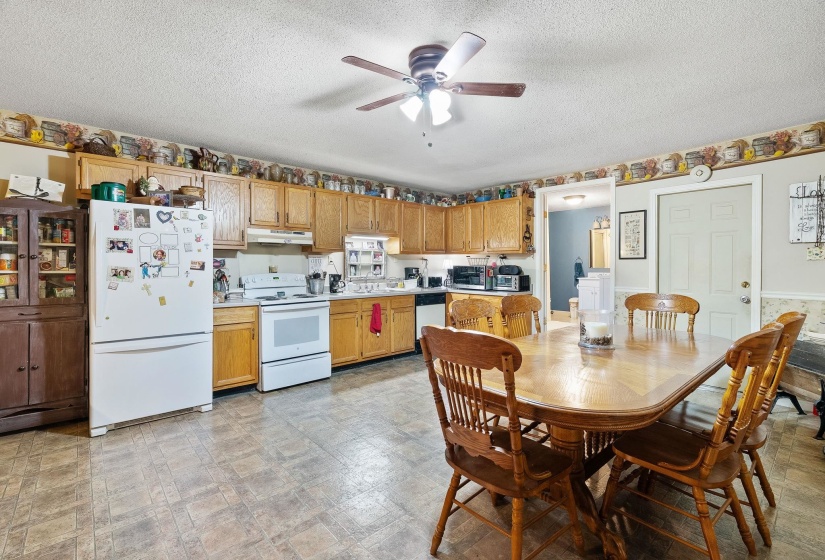 Kitchen with light countertops, white appliances, a textured ceiling, ceiling fan, and light floors