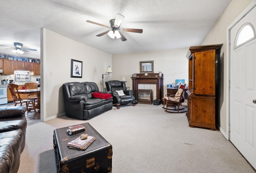 Living area with light colored carpet, a textured ceiling, and ceiling fan