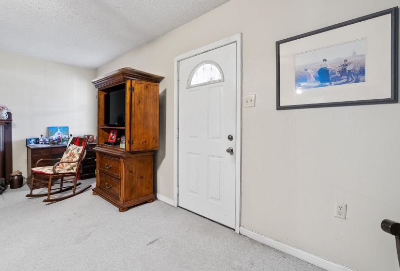 Foyer with a textured ceiling and light colored carpet