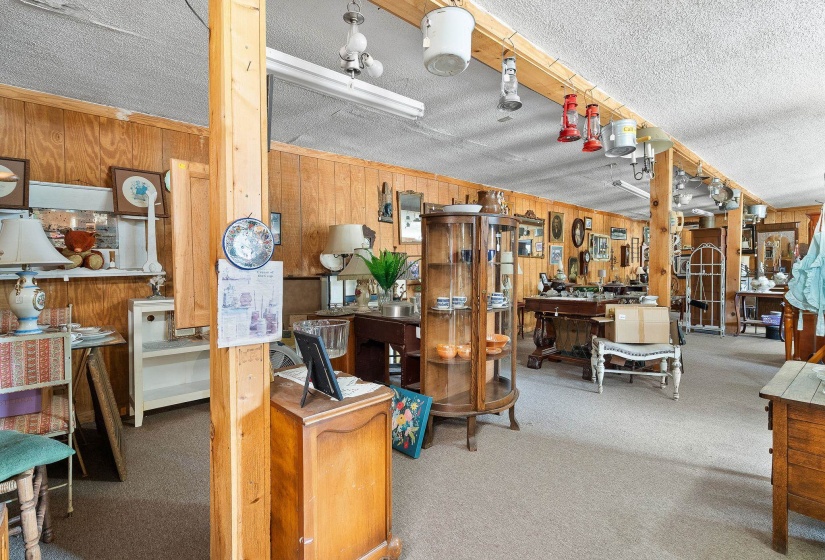 Miscellaneous room featuring light carpet, wooden walls, and a textured ceiling