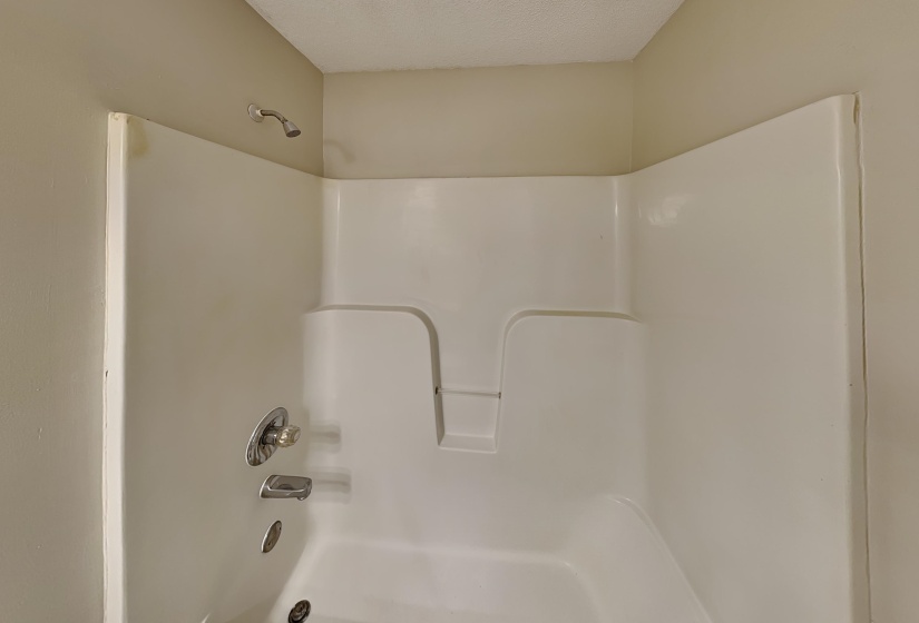 Bathroom featuring bathtub / shower combination and a textured ceiling