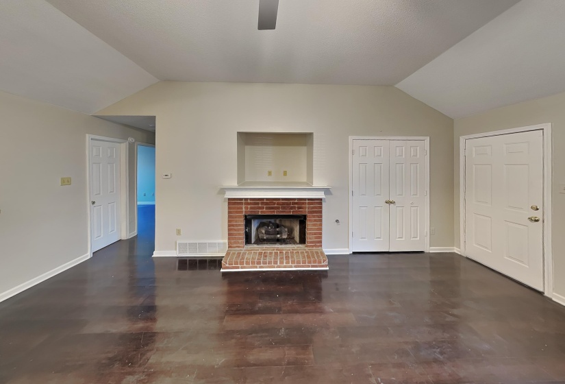 Unfurnished living room featuring dark wood-type flooring, vaulted ceiling, and a fireplace