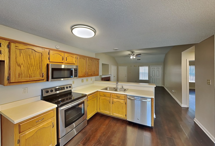 Kitchen with lofted ceiling, appliances with stainless steel finishes, sink, and kitchen peninsula