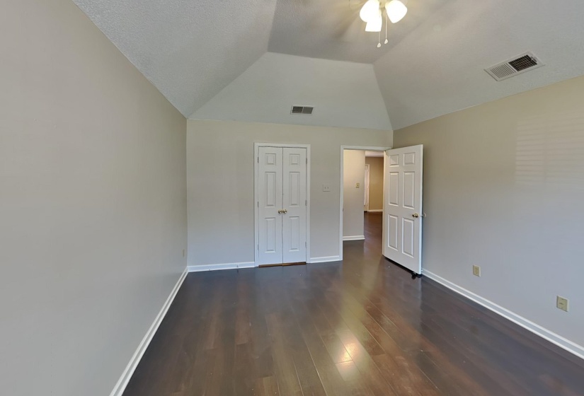 Unfurnished bedroom featuring ceiling fan, a textured ceiling, vaulted ceiling, dark wood-type flooring, and a closet