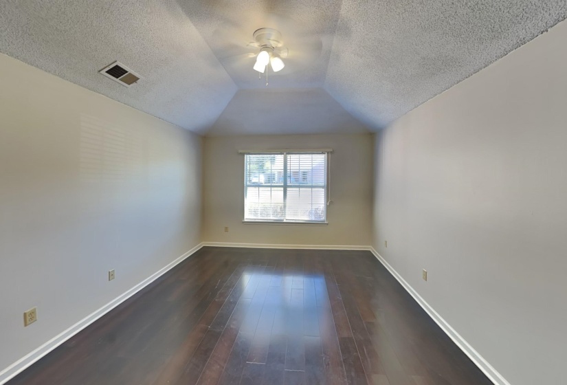 Empty room featuring lofted ceiling, a textured ceiling, dark wood-type flooring, and ceiling fan