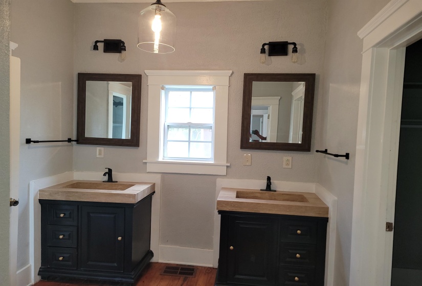 Bathroom featuring two vanities and dark wood-style flooring