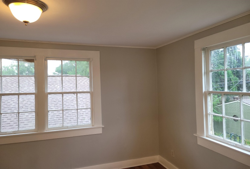 Empty room featuring plenty of natural light, ornamental molding, and dark wood-style flooring