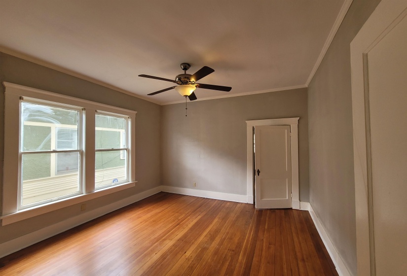 Spare room with crown molding, light wood-type flooring, and a ceiling fan