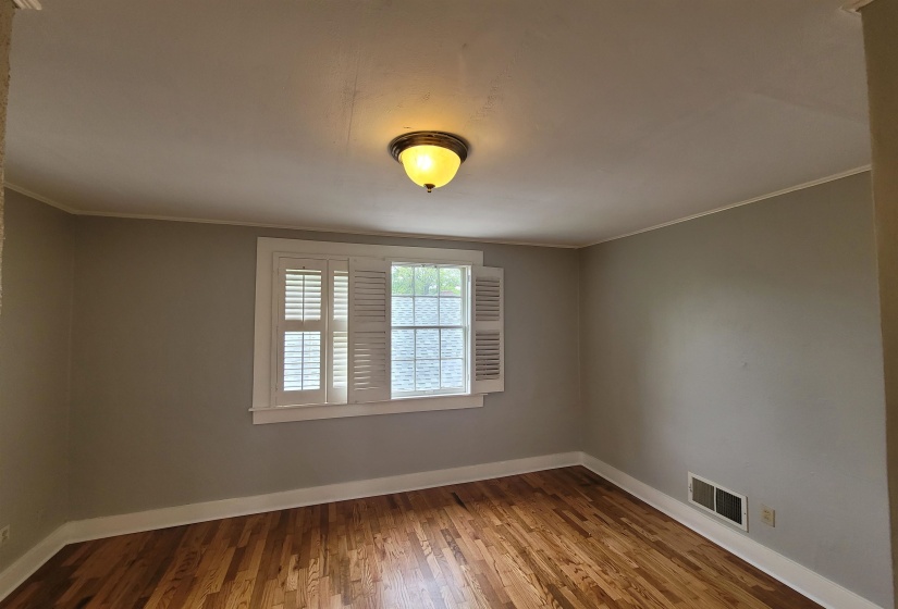 Empty room with ornamental molding and hardwood / wood-style flooring