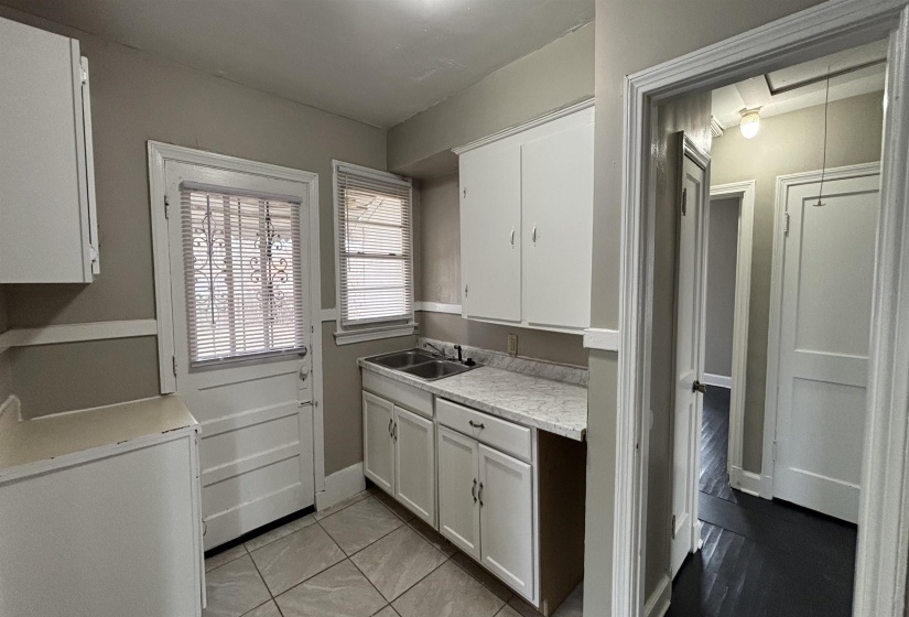 Kitchen with light countertops, white cabinets, white fridge, and light tile patterned floors