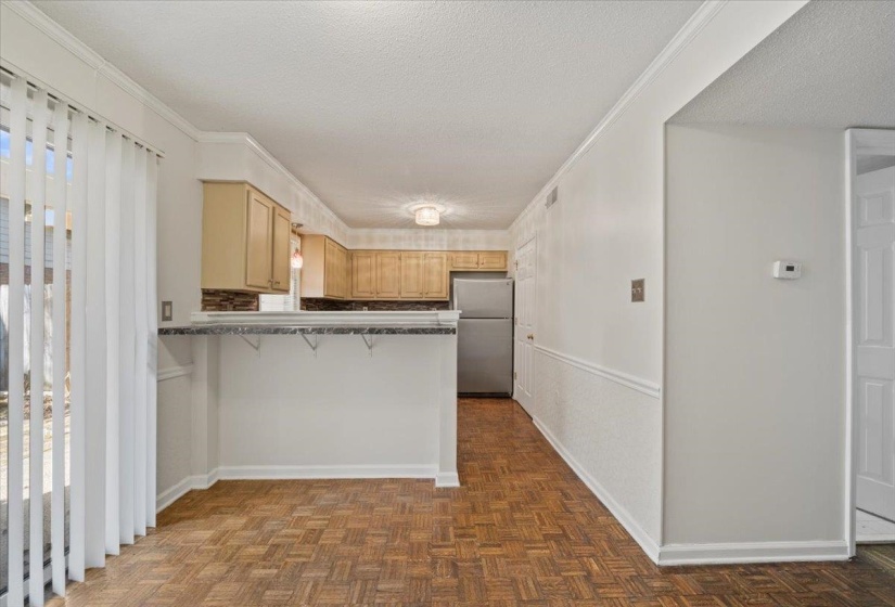 Kitchen featuring a textured ceiling, freestanding refrigerator, a breakfast bar area, a peninsula, and ornamental molding