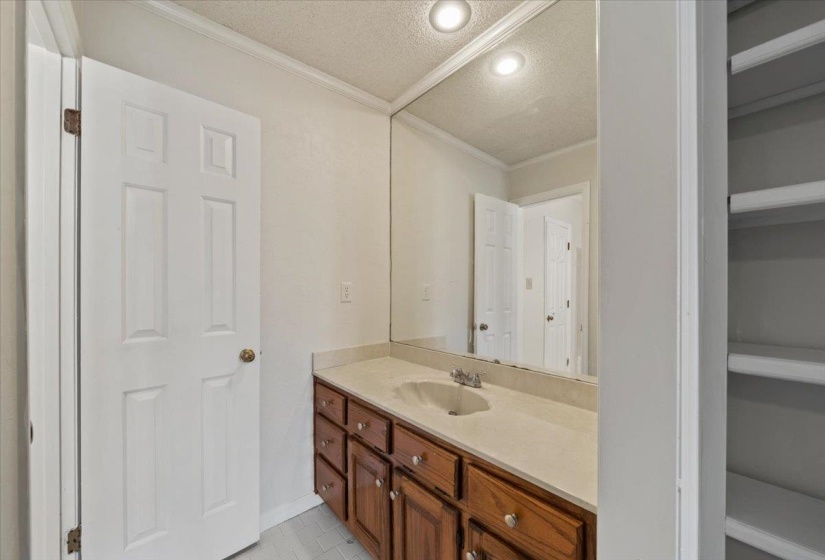 Bathroom featuring a textured ceiling, vanity, ornamental molding, and recessed lighting