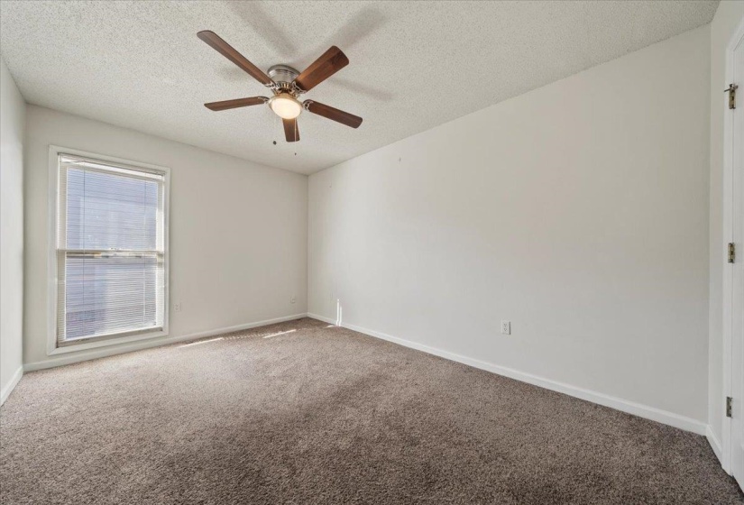 Carpeted spare room featuring a textured ceiling and ceiling fan